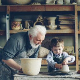 Un petit garçon apprend la poterie avec son grand-père. Il façonne l'argile pour fabriquer un pot sur le tour du potier.